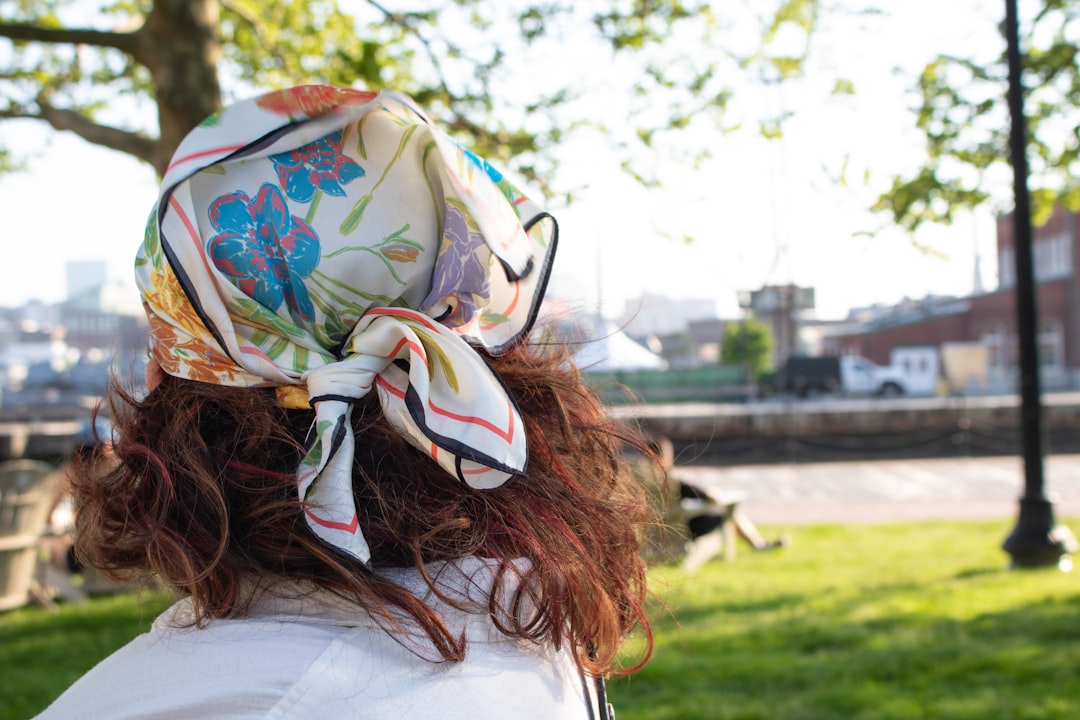 Woman adjusts silk scarf on curly hair