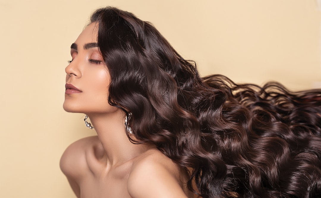 Woman applying mousse to wavy hair in bathroom