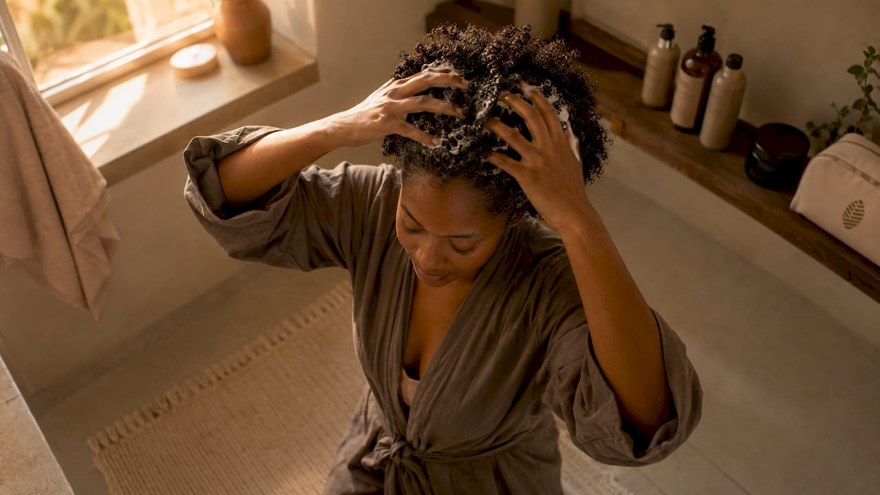 Woman cleansing curly scalp in sunlight