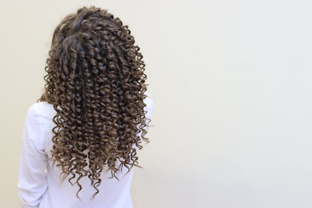 Woman defining type 3 curls with cream in bathroom