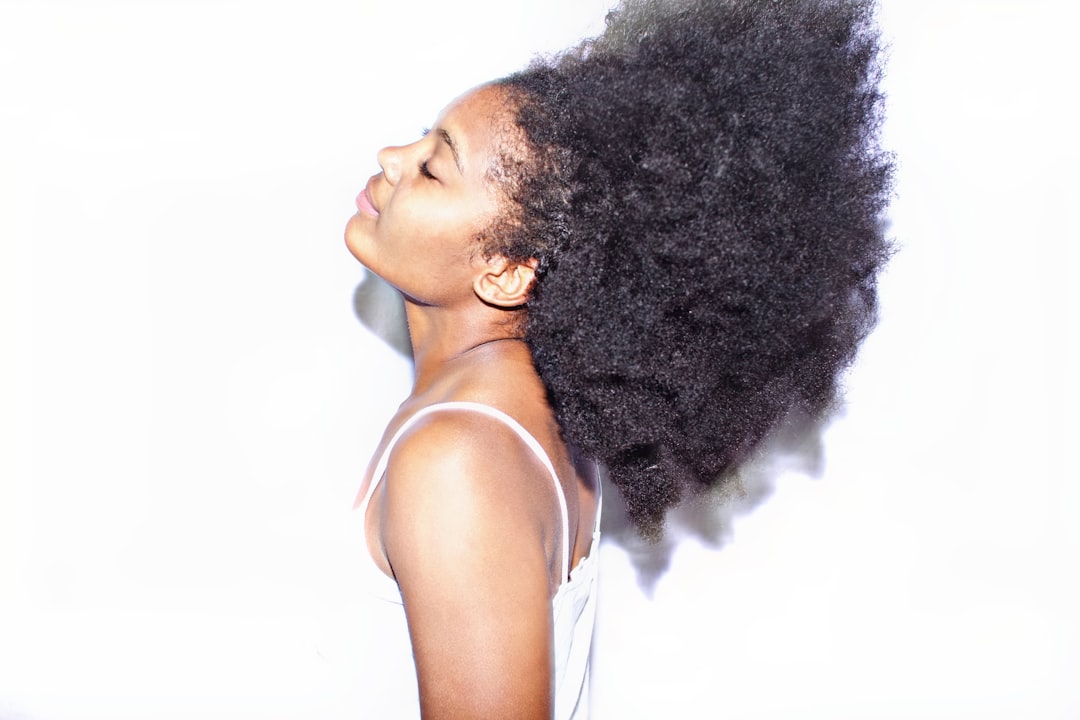 Black woman moisturizes afro hair in living room