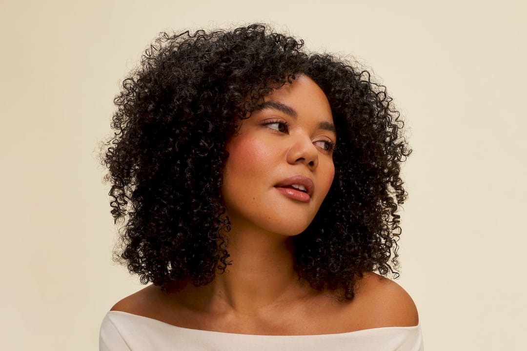 Woman clarifying curly hair at bathroom sink