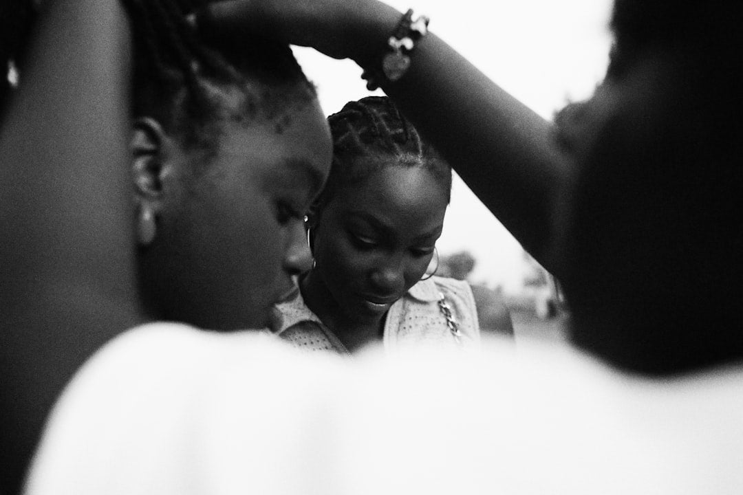 Two women with natural hair braiding at home