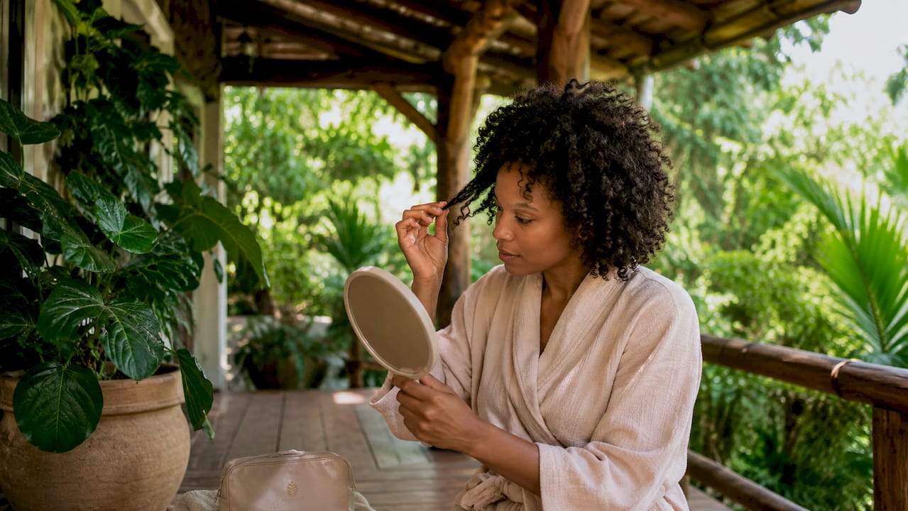 Woman examining damaged curls in mirror