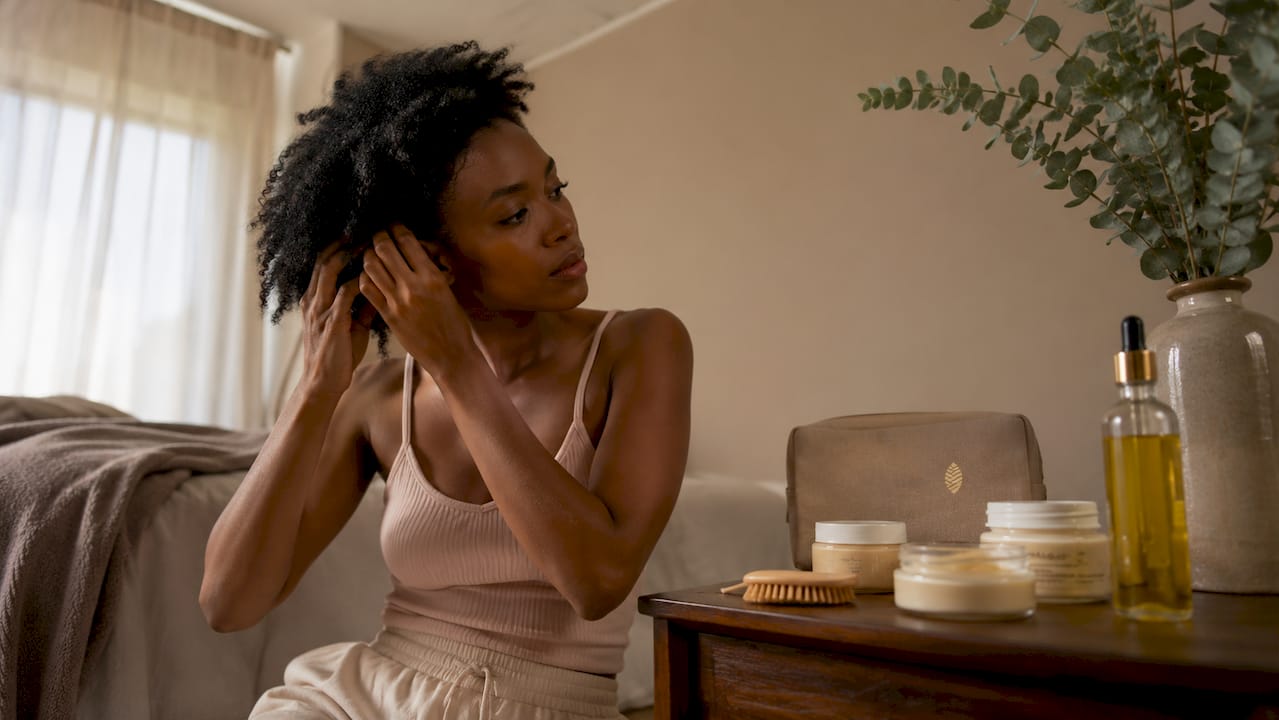 Woman applying oil to low porosity curly hair