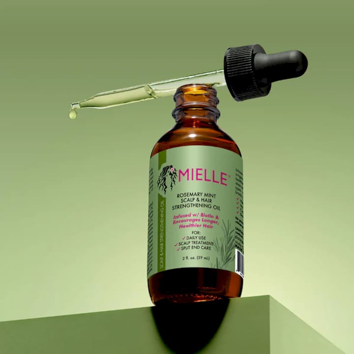 Woman applying scalp oil to natural textured hair
